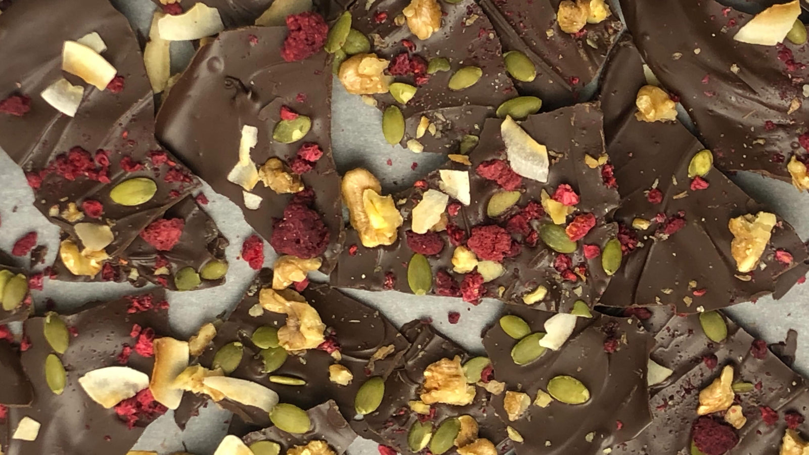 Keto friendly chocolate bark with nuts seeds and berries on top