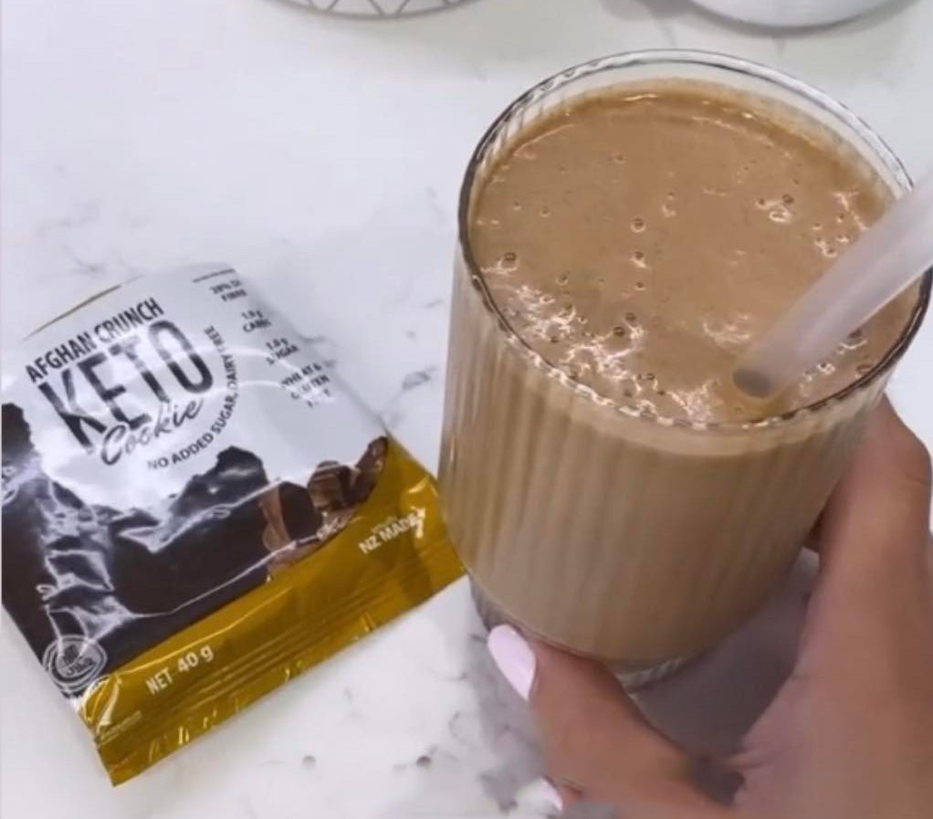 keto cookies and cream protein shake in hand beside keto afghan crunch cookie